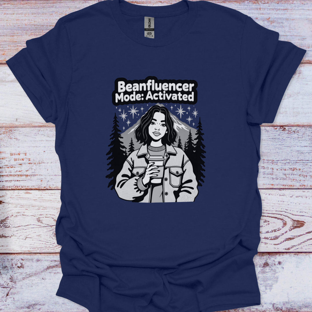 Navy blue t-shirt with graphic design of a person holding a coffee cup and text 'Beanfluencer Mode: Activated' on a wooden surface.