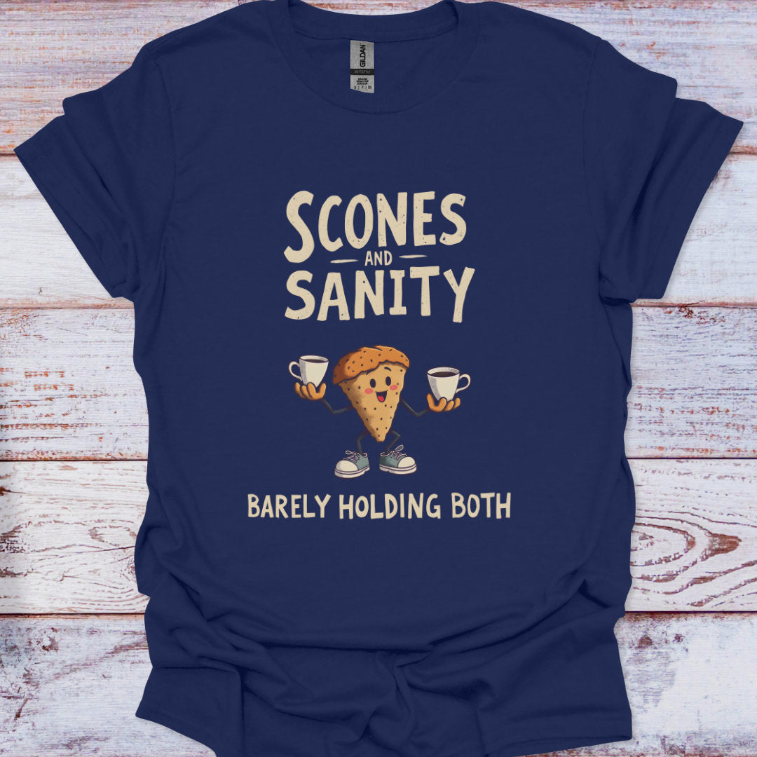 Navy blue t-shirt with 'Scones and Sanity Barely Holding Both' graphic on a wooden surface