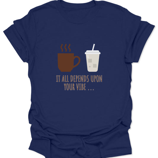 Graphic tee on navy blue fabric featuring a brown steaming coffee mug and a light beige iced coffee cup with the text "IT ALL DEPENDS UPON YOUR VIBE..." in thin brown lettering.