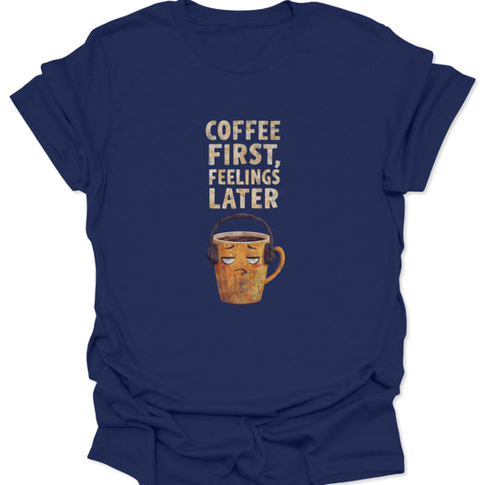 Navy t-shirt featuring grumpy mug with headphones and "Coffee First, Feelings Later" text, funny introvert style.