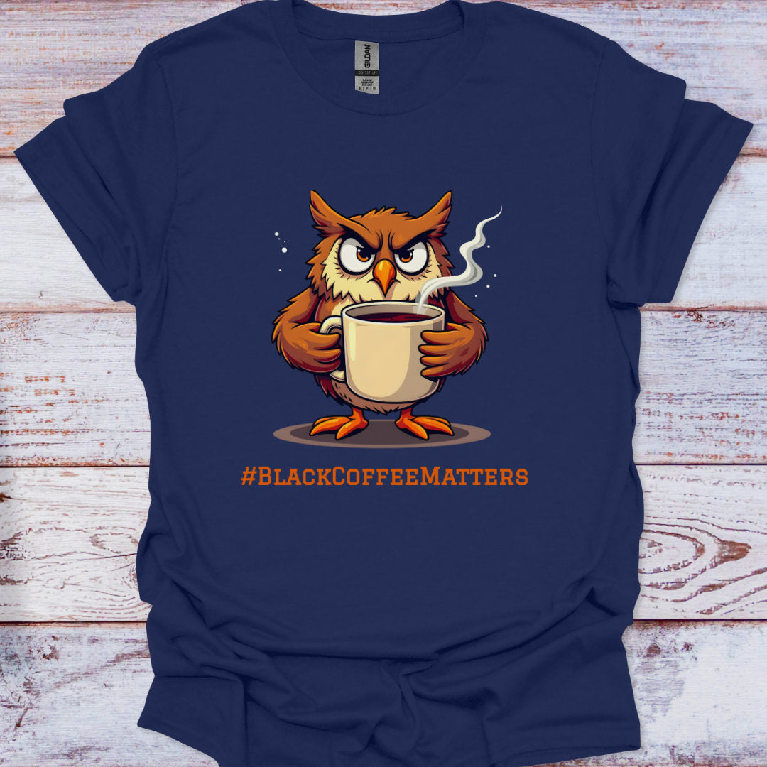 Navy blue t-shirt with an owl holding a coffee cup and '#BLACKCOFFEEMATTERS' text on a wooden surface.