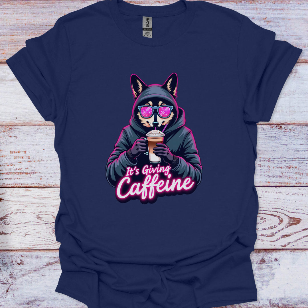 Navy blue t-shirt with a graphic of a fox holding a coffee cup and text 'It's Giving Caffeine' on a wooden surface.