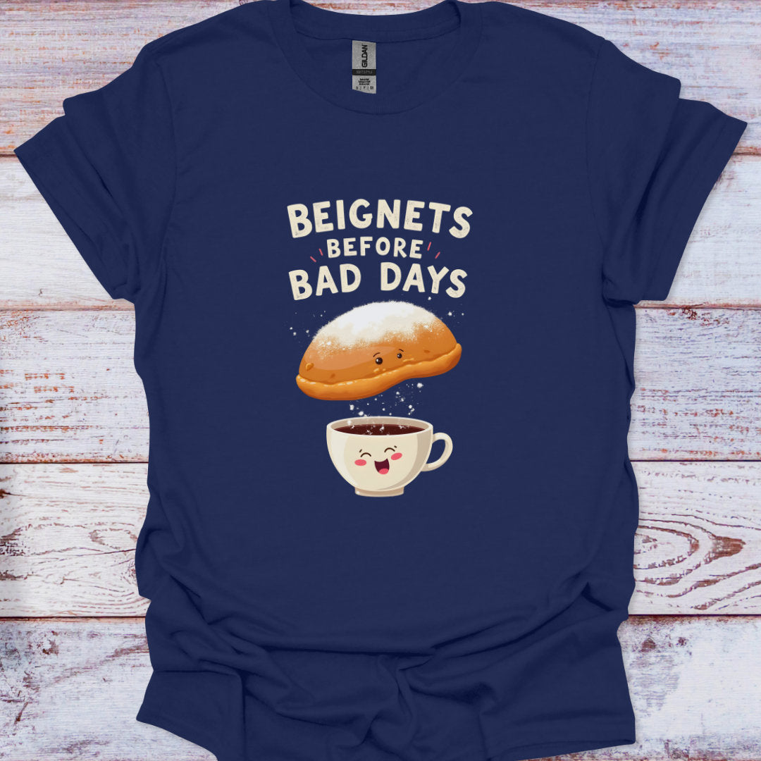 Navy blue t-shirt with a cartoon beignet and coffee cup graphic and text 'Beignets Before Bad Days' on a wooden surface.