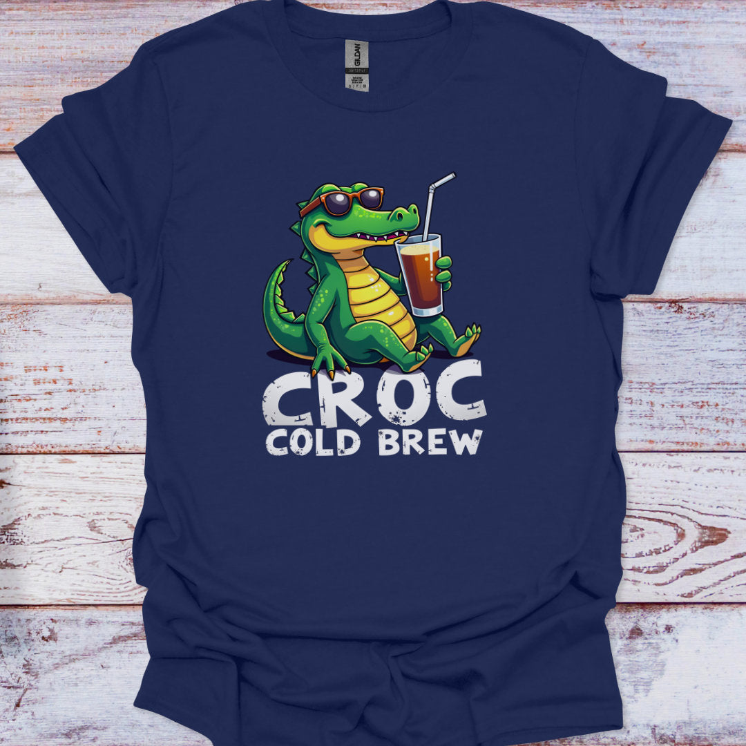 Navy blue t-shirt with a green crocodile holding a cup labeled 'Croc Cold Brew' on a wooden surface.