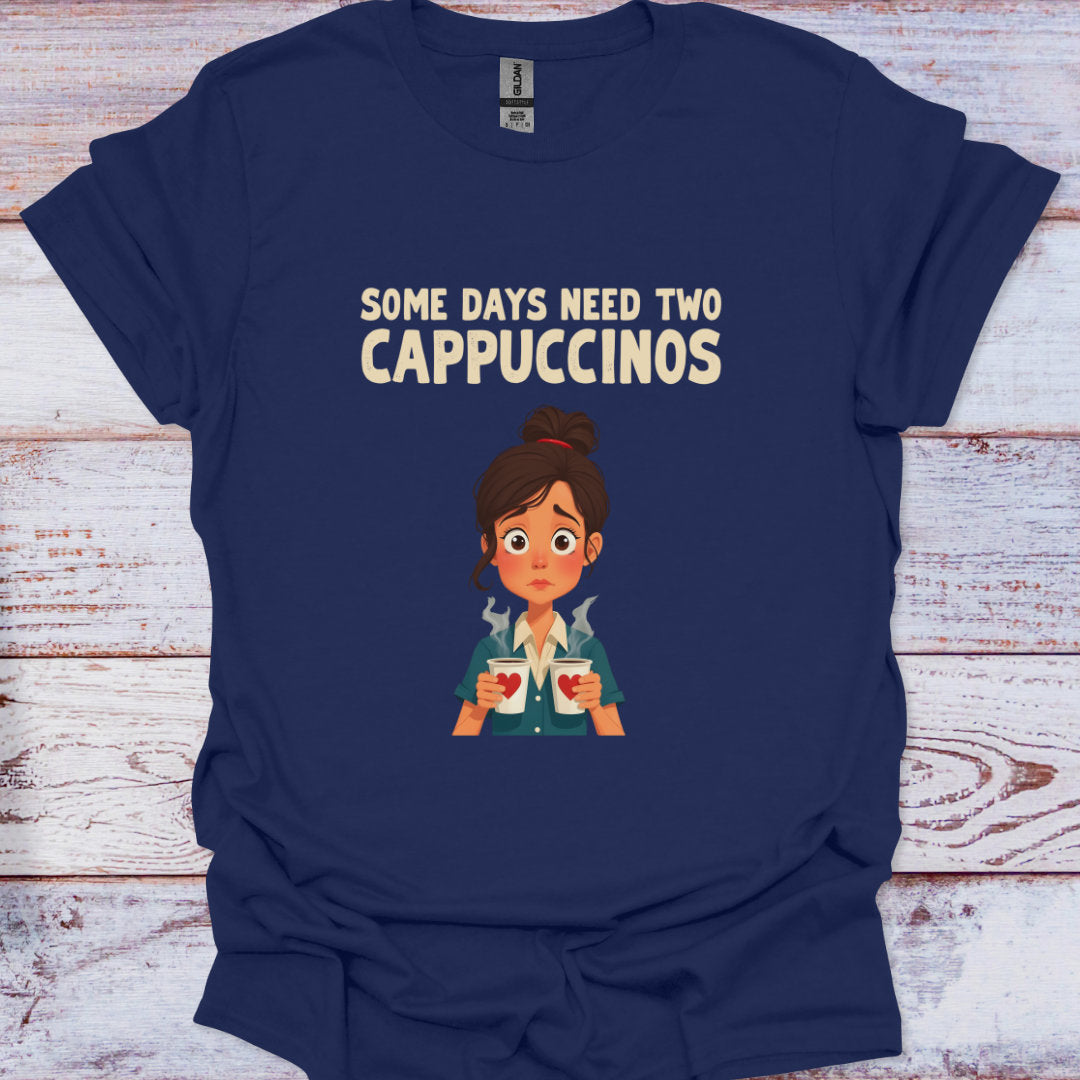 Navy blue t-shirt with cartoon character and text 'Some days need two Cappuccinos' on a wooden surface.