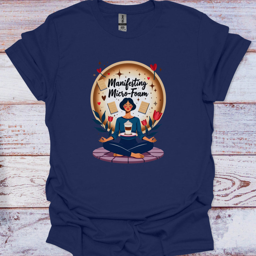 Navy blue t-shirt with a graphic of a person meditating and text 'Manifesting Micro-Foam' on a wooden surface.