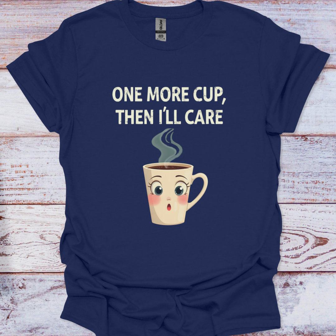 Navy blue t-shirt with a cartoon coffee cup and text 'One more cup, then I'll care' on a wooden surface.