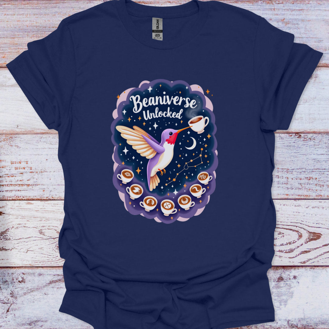 Navy blue t-shirt with a graphic design of a hummingbird, coffee cups, and 'Beaniverse Unlocked' text on a wooden surface.