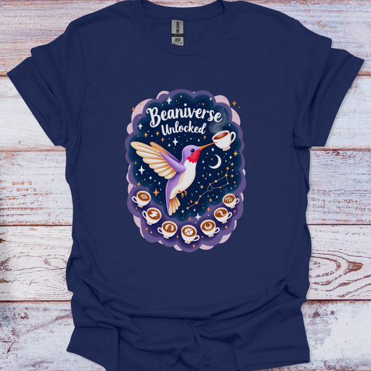 Navy blue t-shirt with a graphic design of a hummingbird, coffee cups, and 'Beaniverse Unlocked' text on a wooden surface.