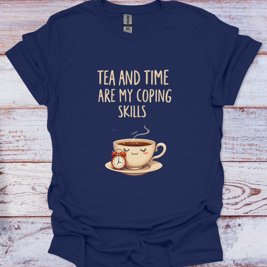 Navy blue t-shirt with a graphic of a teacup and clock, and text 'Tea and time are my coping skills' on a wooden surface.