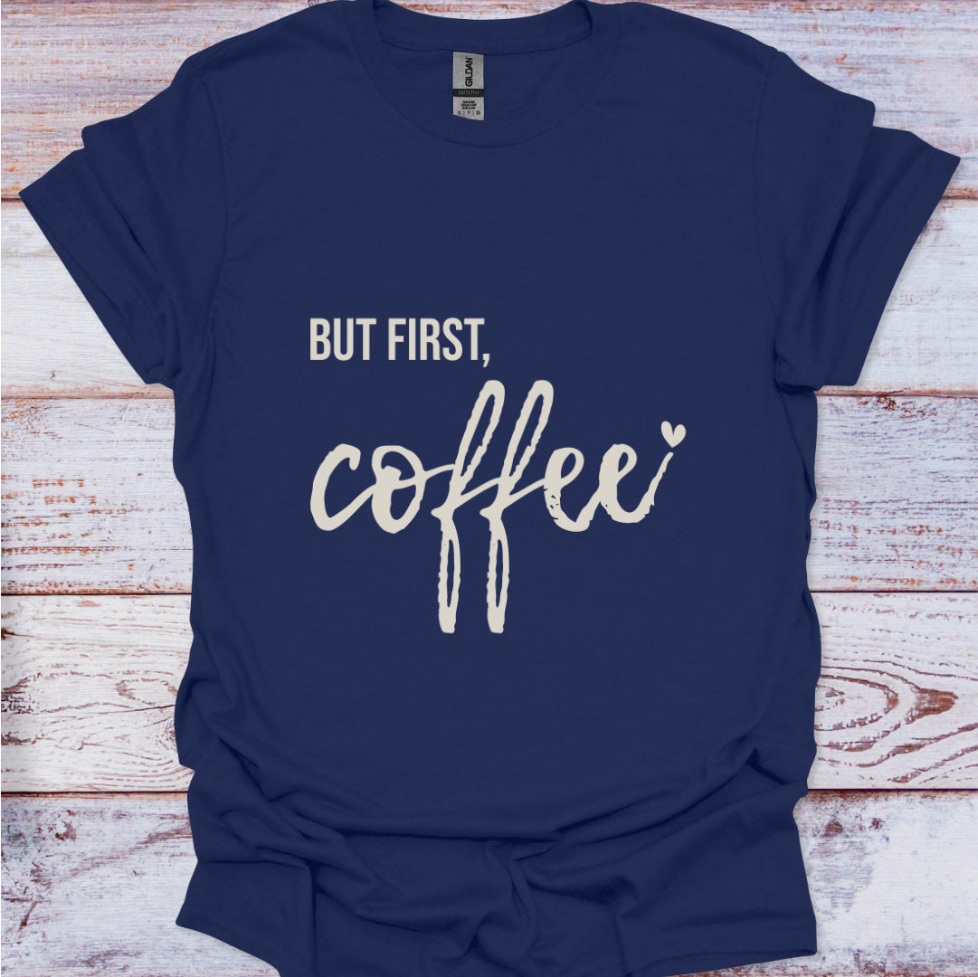 Navy blue t-shirt with 'But first, coffee' text on a wooden surface