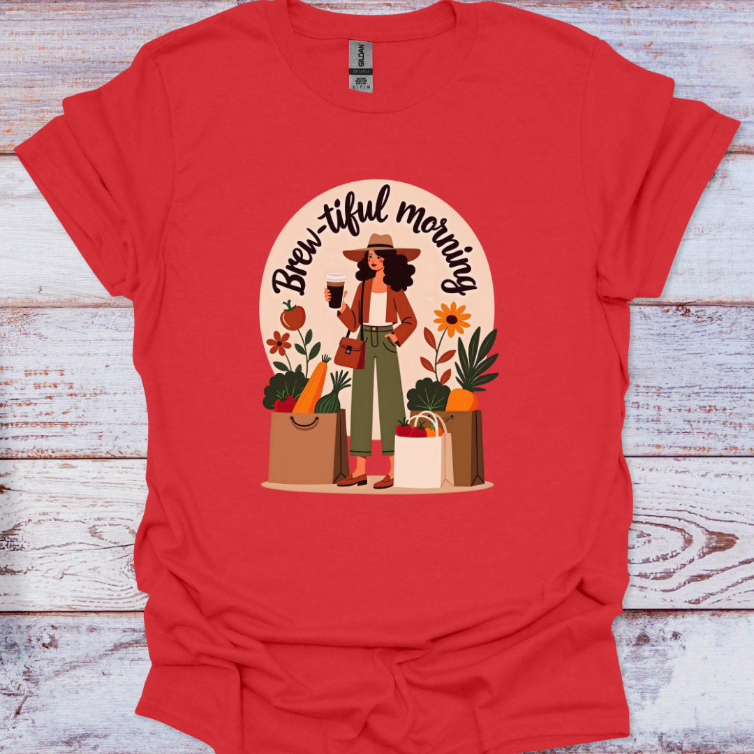 Red t-shirt with a graphic of a woman holding a coffee cup and shopping bags, with 'Brew-iful morning' text, on a wooden surface.