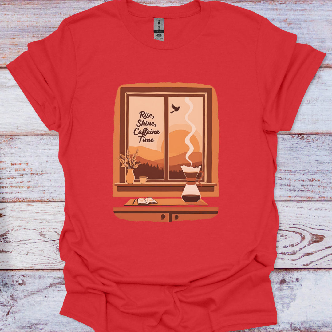 Red t-shirt with a graphic design of a window, coffee maker, and text 'Rise, Shine, Caffeine Time' on a wooden surface.