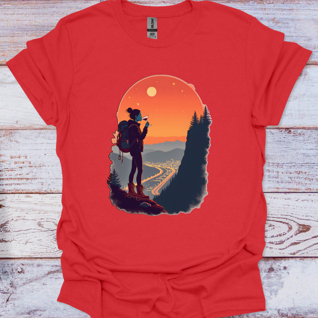 Red t-shirt with a graphic of a person with a backpack and scenic design on a wooden surface