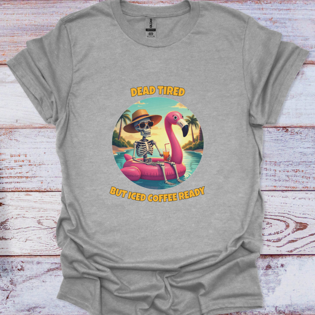Gray t-shirt with a skeleton on a flamingo float graphic and text 'Dead Tired But Iced Coffee Ready' on a wooden surface.