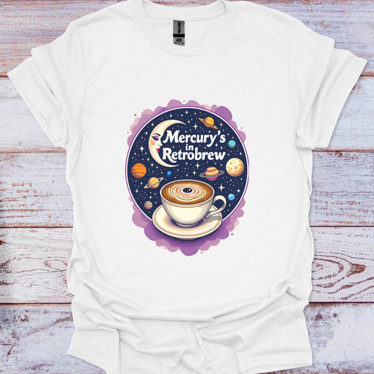 White t-shirt with a graphic design of a coffee cup and celestial elements on a wooden surface
