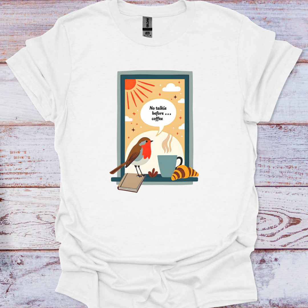 White t-shirt with a colorful graphic of a bird, cup, and book on a wooden surface