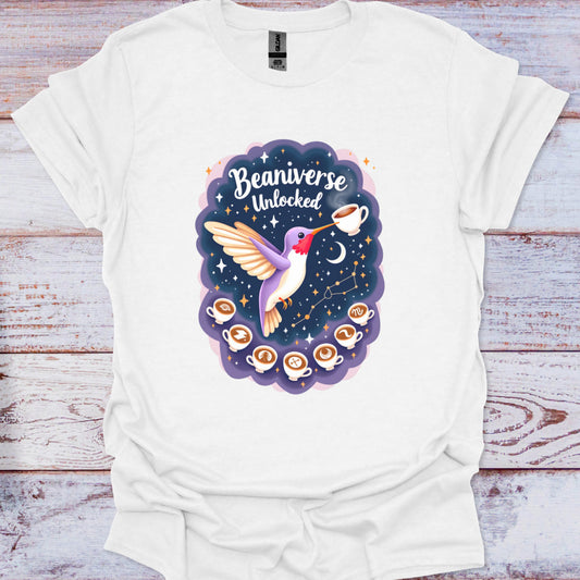 White t-shirt with a colorful graphic design featuring a hummingbird and coffee cups on a wooden surface.