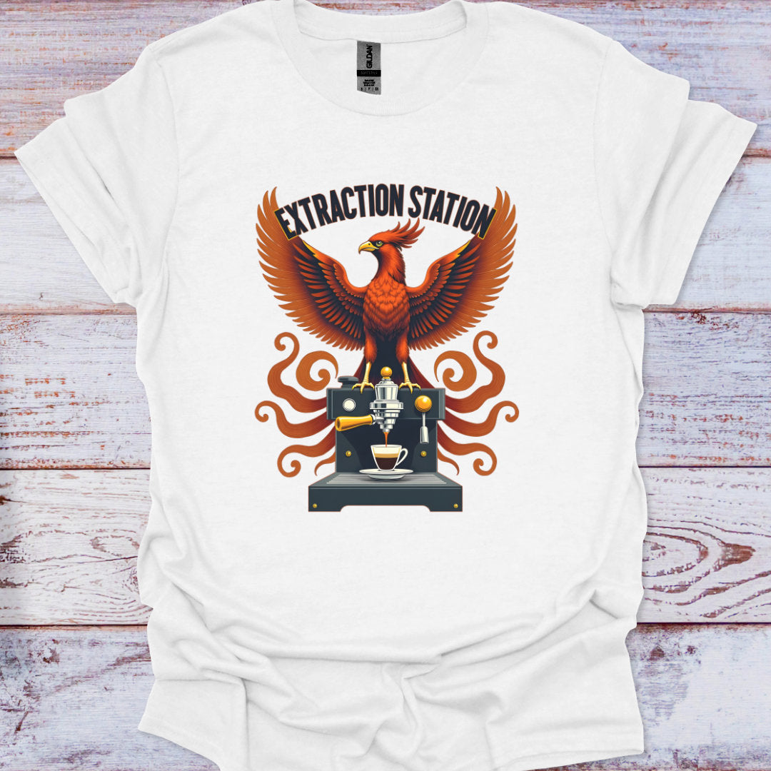 White t-shirt with a graphic design of an mythic phoenix bird and coffee machine on a wooden surface