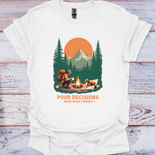 White t-shirt with a graphic by a campfire in a forest, with text 'Pour Decisions Make Good Stories' on a wooden surface.