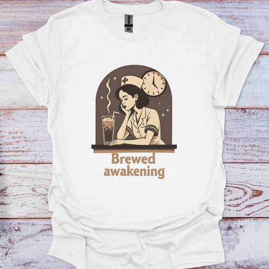 White t-shirt with a graphic design of a woman reading a book and drinking coffee, with text 'Brewed awakening' on a wooden surface.