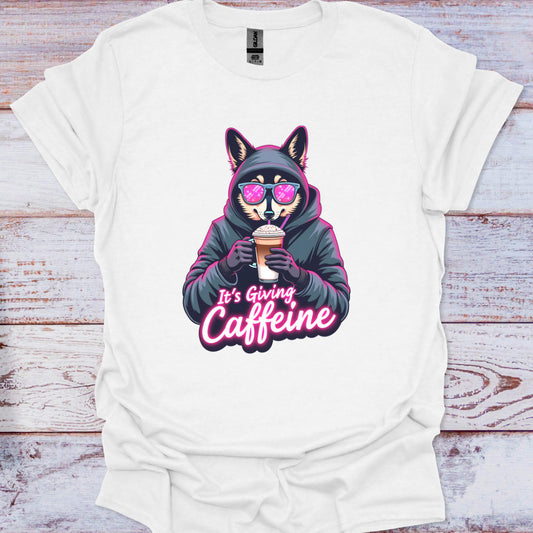 White t-shirt with a graphic of a fox in a hoodie holding a coffee cup and text 'It's Giving Caffeine' on a wooden surface.