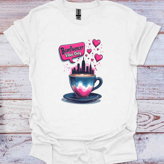 White t-shirt with a colorful coffee cup graphic and text on a wooden surface