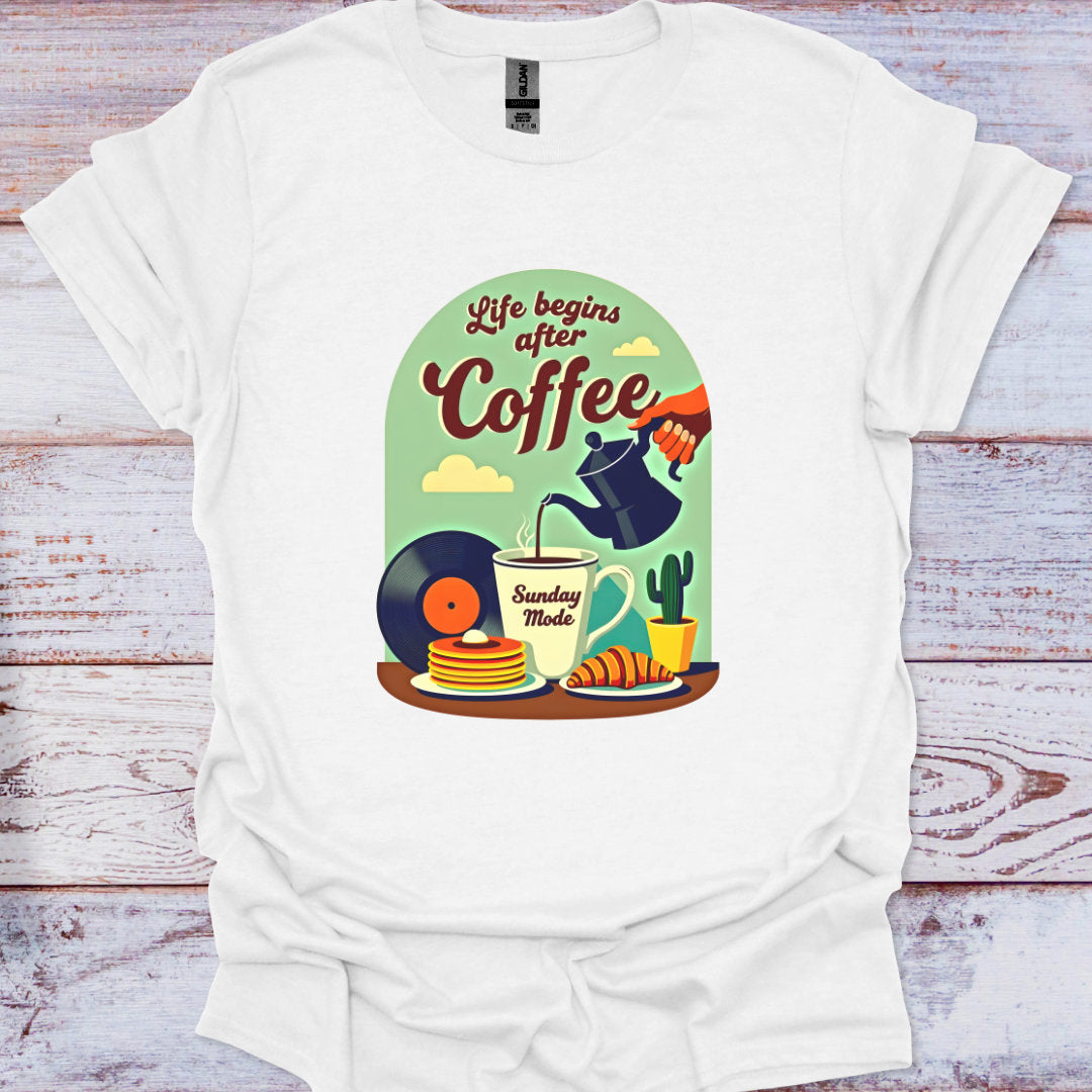 White t-shirt with a colorful graphic design featuring coffee-themed illustrations on a wooden surface.