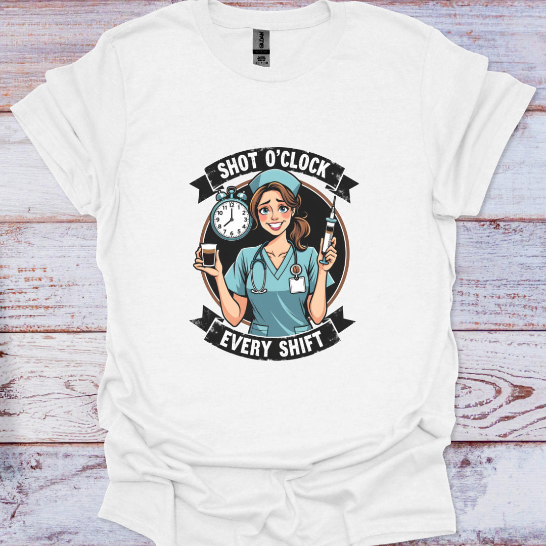 White t-shirt with a graphic of a nurse and text 'Shot O'Clock Every Shift' on a wooden surface.