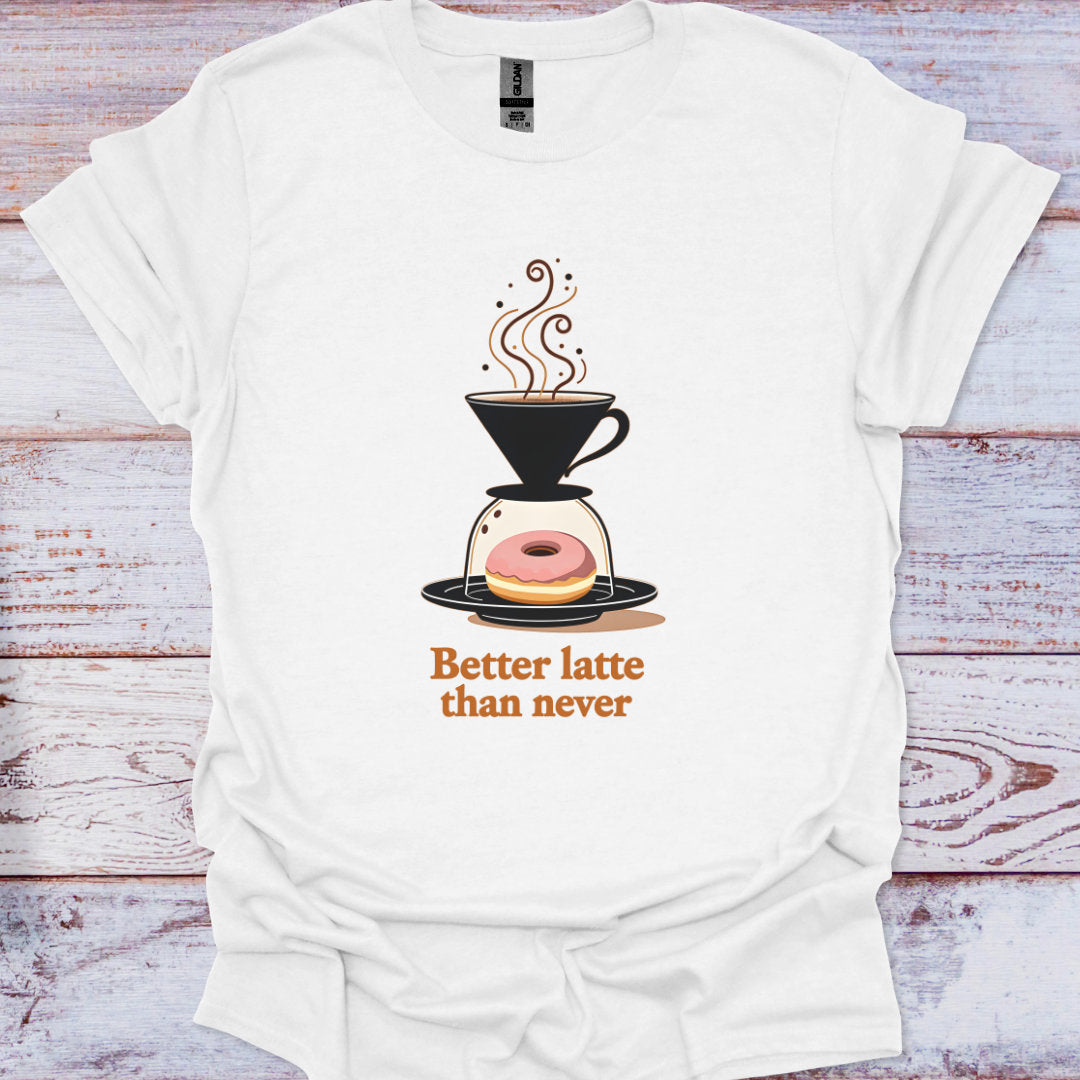 White t-shirt with a coffee-themed graphic and text 'Better latte than never' on a wooden surface.
