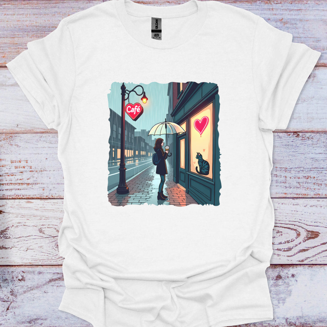 White t-shirt with a graphic of a person with an umbrella standing in front of a cafe with a heart on the door, on a wooden surface.