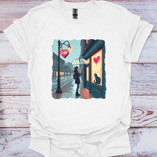 White t-shirt with a graphic of a person with an umbrella standing in front of a cafe with a heart on the door, on a wooden surface.