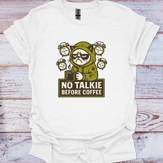 White t-shirt with a graphic of a character holding a coffee cup and text 'No Talkie Before Coffee' on a wooden surface.