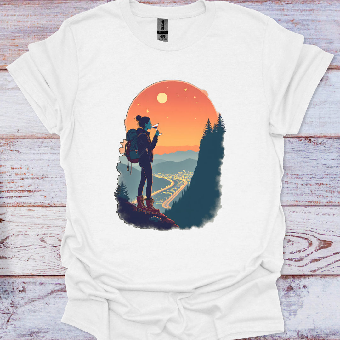 White t-shirt with a graphic of a person with a backpack and scenic landscape on a wooden surface