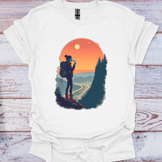 White t-shirt with a graphic of a person with a backpack and scenic landscape on a wooden surface