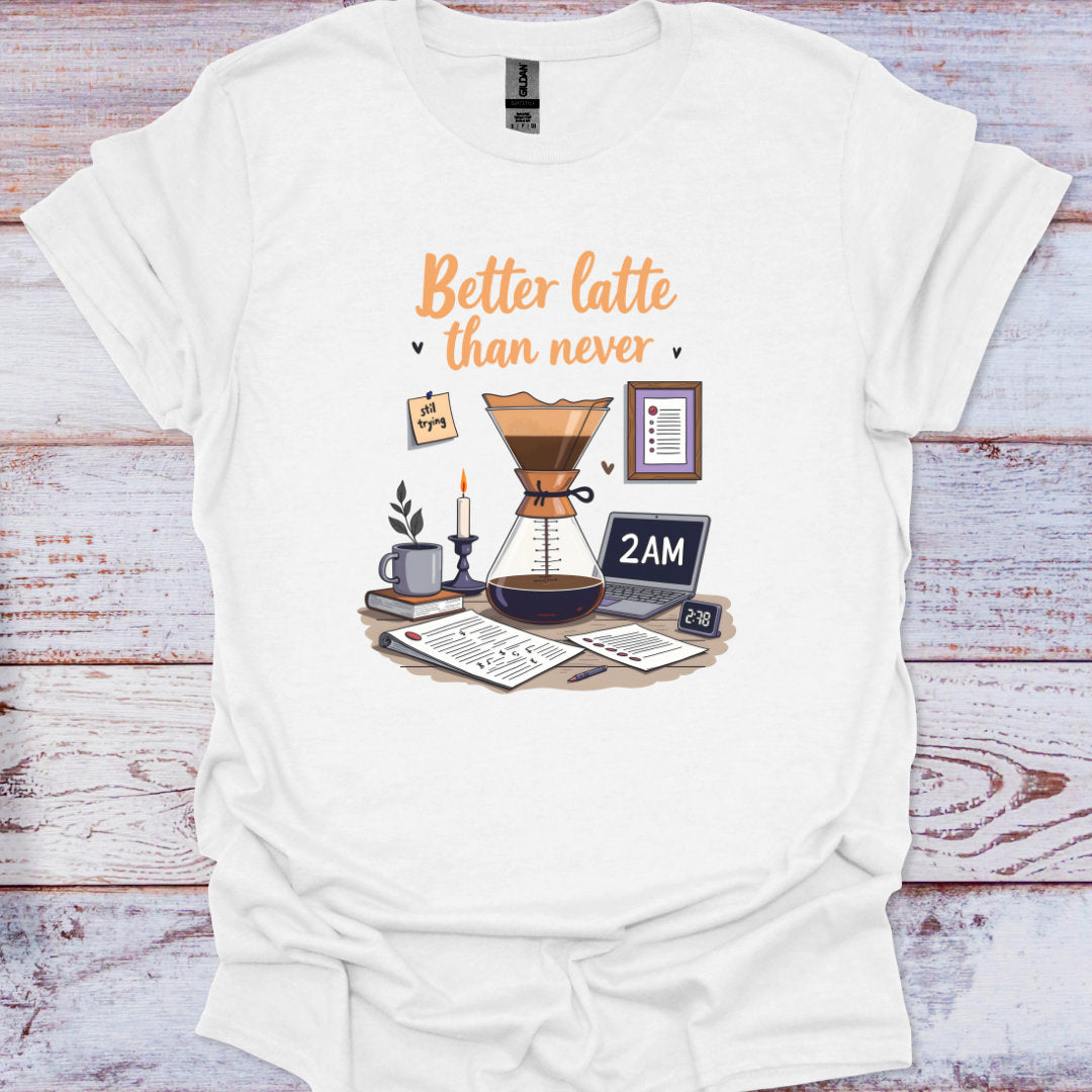 White t-shirt with a coffee-themed graphic and text 'Better latte than never' on a wooden surface.